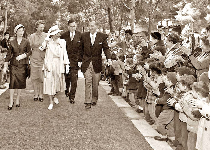 1959  - ילדי הגנים הסמוכים מרעים למלכת בלגיה שצועדת עם הפמליה שלה לעבר בית הנשיא בגן הכוזרי בקטע שבין רחוב אבנרבנאל לבין המדרגות המובילות לצריף הנשיא. 